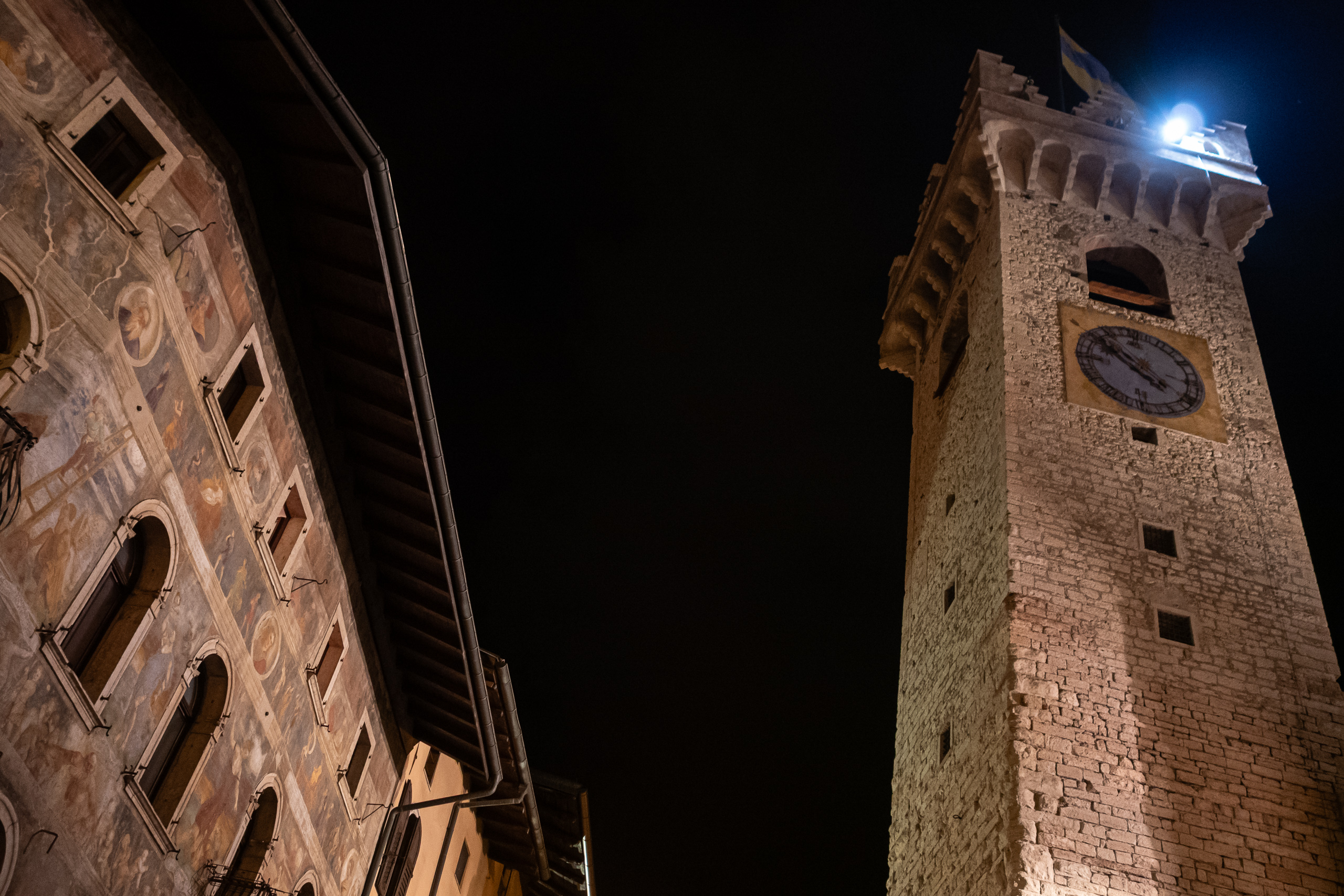 Trento bei Nacht – Freskenfassade und der Torre Civica